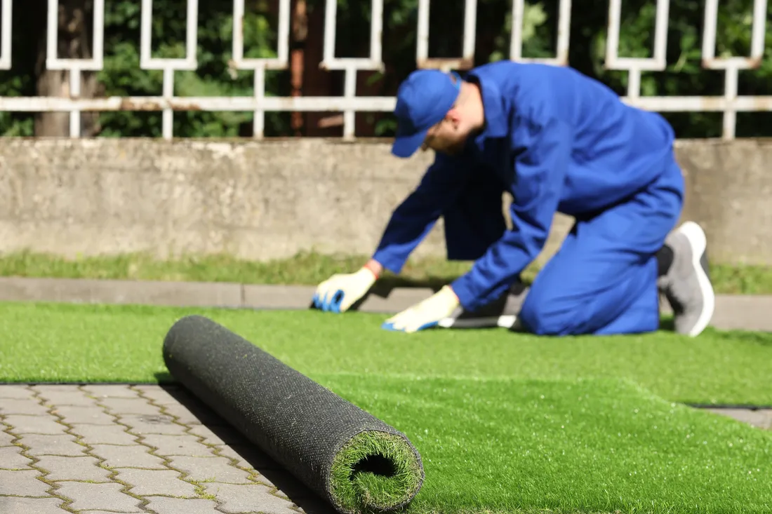 Artificial turf being rolled out across a residential backyard