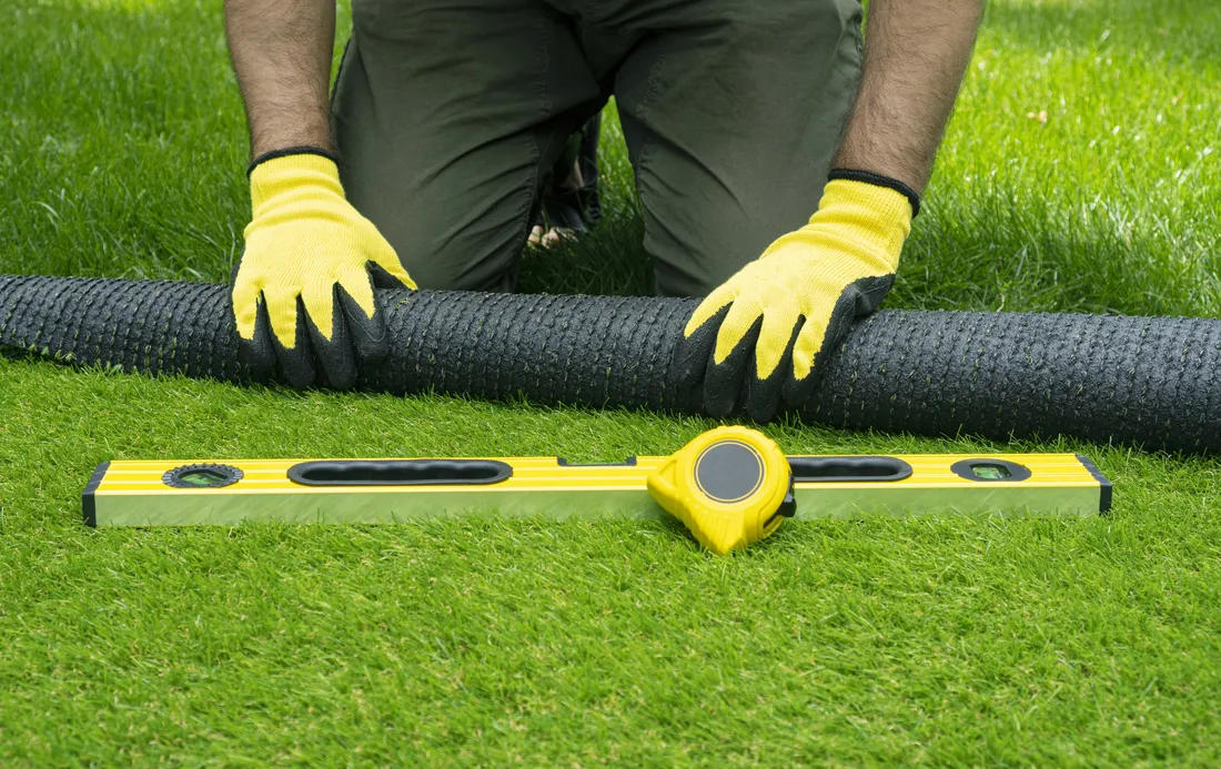 An installer measuring a lawn area before an artificial turf installation